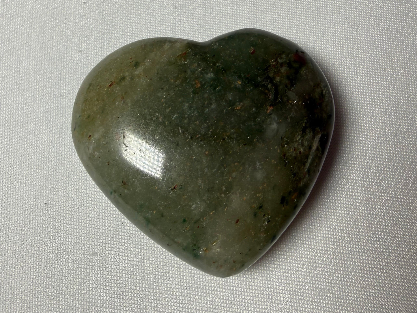 Heart-shaped green stone on a gray fabric background