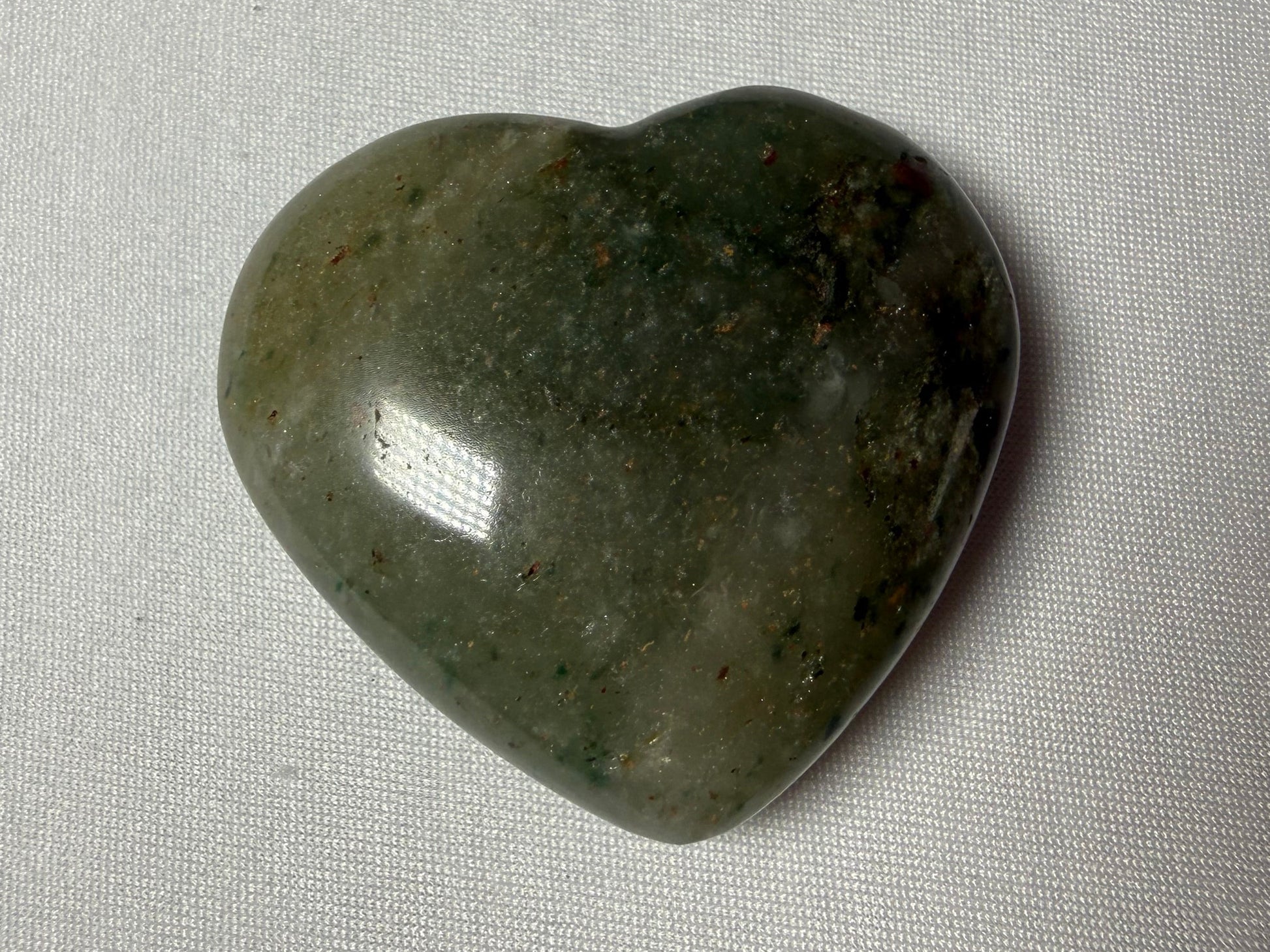 Heart-shaped green stone on a gray fabric background
