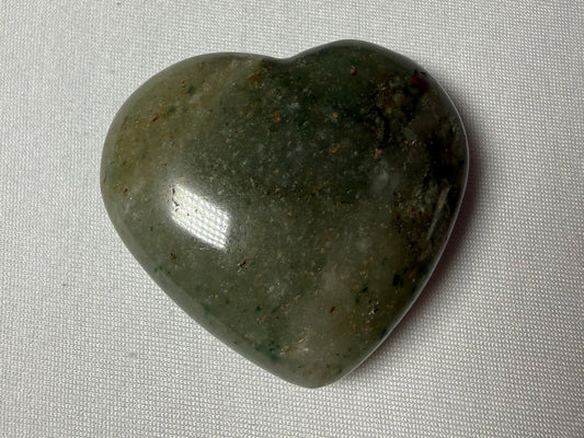 Heart-shaped green stone on a gray fabric background