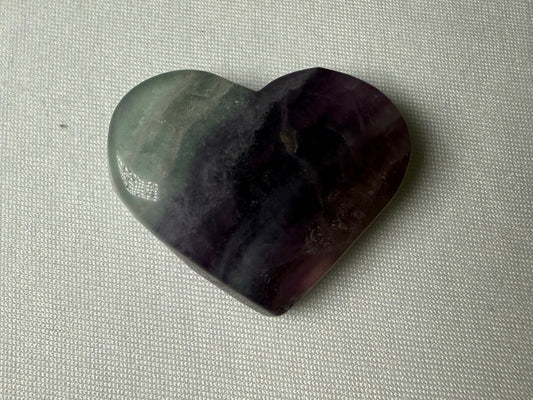 Heart-shaped stone on a textured beige surface