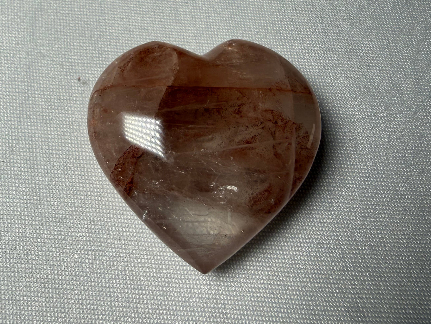 Heart-shaped brown stone on a gray fabric background