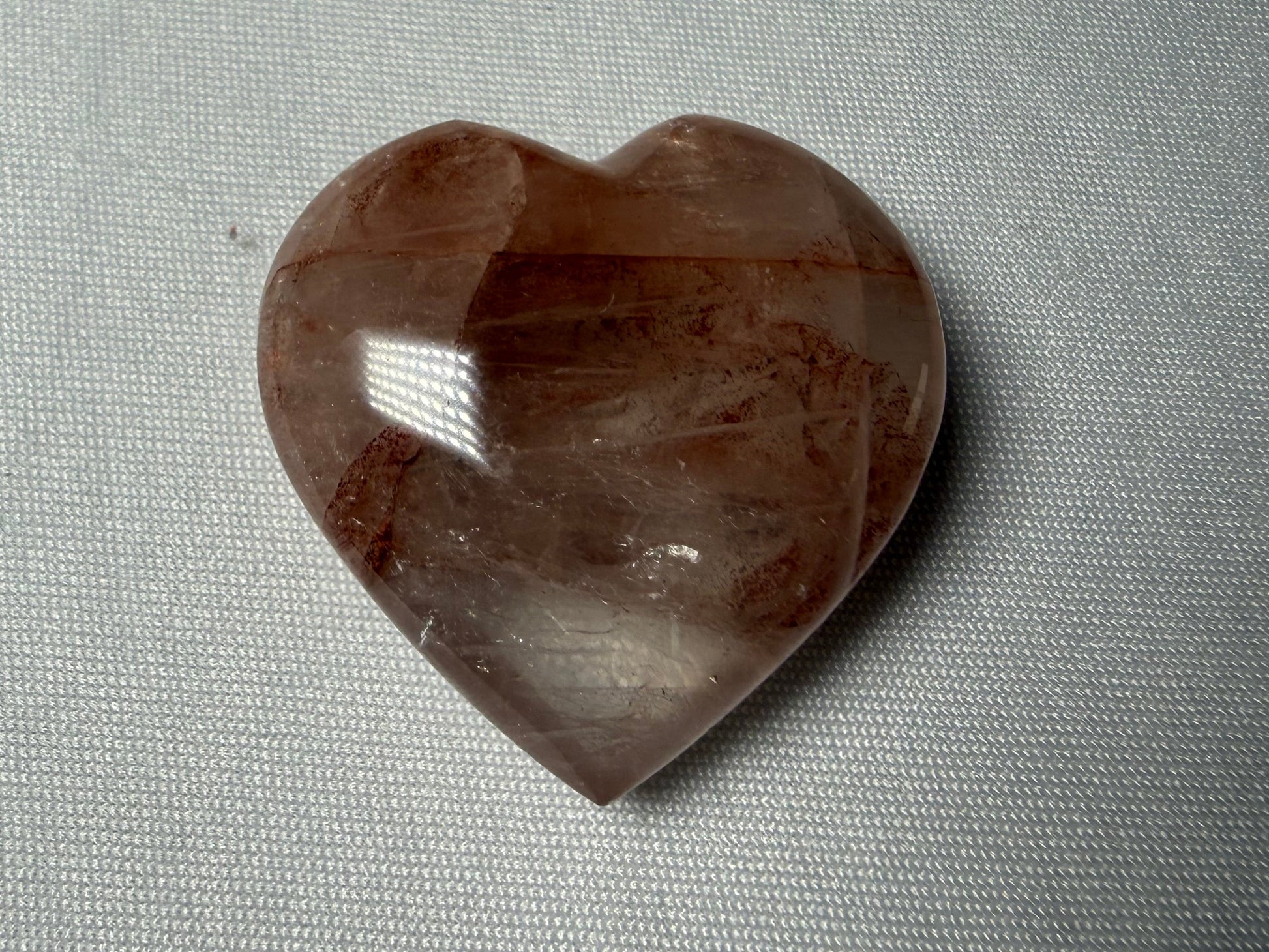 Heart-shaped brown stone on a gray fabric background