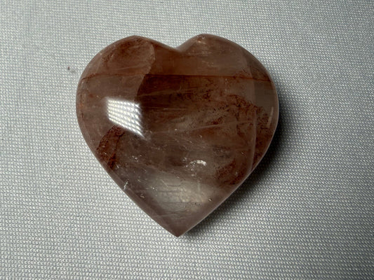 Heart-shaped brown stone on a gray fabric background